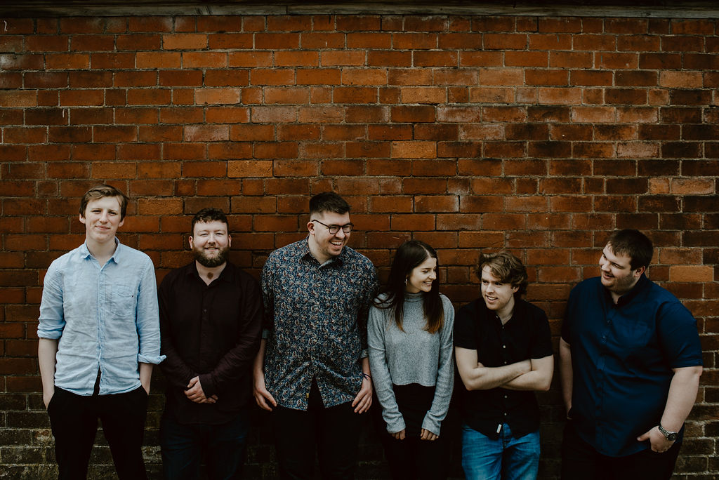 The full TRIP lineup laughing in front of a brick wall